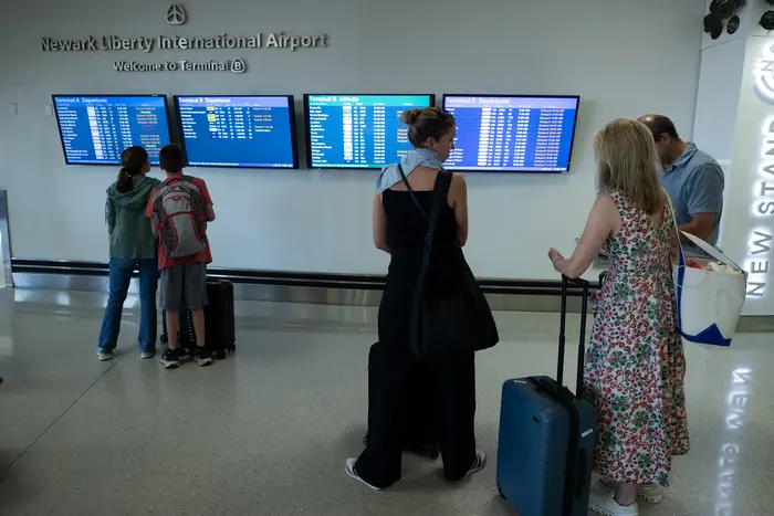 Flyers looking at information boards at Newark Airport.